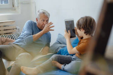 Junge fotografiert mit Tablet-PC spielerischen Großvater, der ihn zu Hause neckt - JOSEF12188