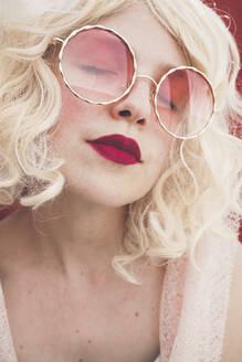 Blond woman with eyes closed wearing red sunglasses - SVCF00128