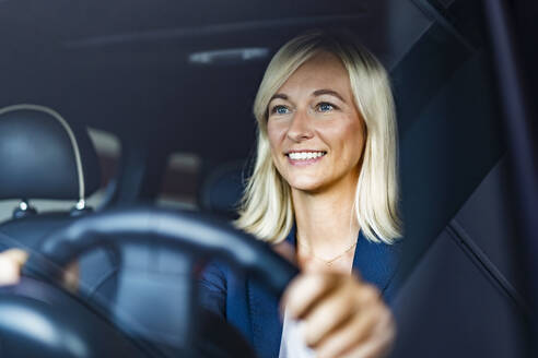 Smiling businesswoman driving car seen through windshield - DIGF18623