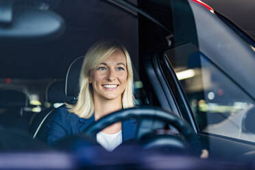 Glückliche Geschäftsfrau mit blondem Haar fährt Auto durch die Windschutzscheibe gesehen - DIGF18624