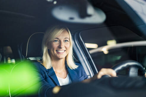 Mature businesswoman sitting in car seen through windshield - DIGF18625