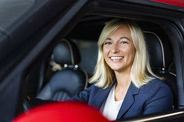 Glückliche Geschäftsfrau mit blondem Haar im Auto sitzend - DIGF18628