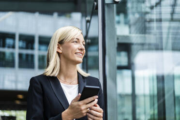 Lächelnde blonde Geschäftsfrau mit Mobiltelefon - DIGF18640