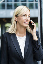 Smiling businesswoman with blond hair talking on phone - DIGF18642