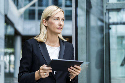 Blond mature businesswoman standing with tablet PC - DIGF18643