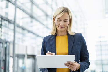 Lächelnde Geschäftsfrau mit digitalisiertem Stift auf einem Tablet-PC - DIGF18652