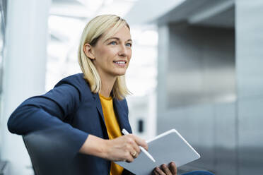 Smiling businesswoman sitting with tablet PC - DIGF18668