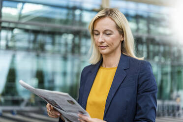 Businesswoman with blond hair reading newspaper - DIGF18687