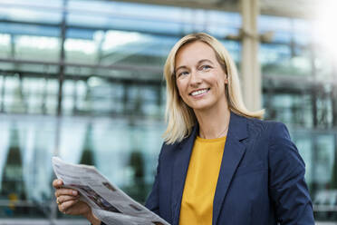 Smiling blond businesswoman with newspaper - DIGF18689