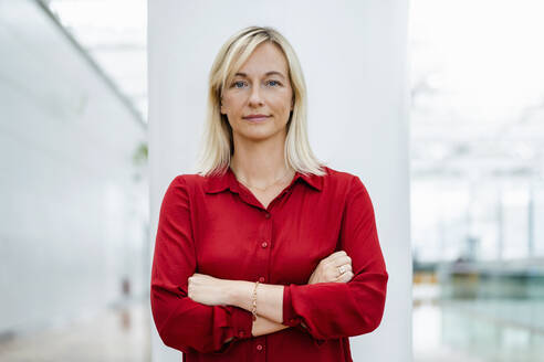 Confident businesswoman standing in front of column - DIGF18696