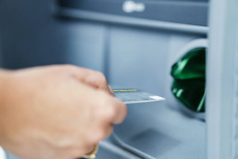 Hand einer Frau, die eine Kreditkarte in einen Geldautomaten einführt - DIGF18717