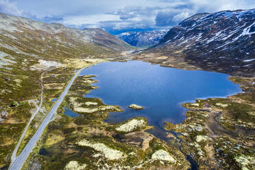 Norwegen, Viken, Drohnenansicht einer Straße, die an einem See im Hemsedalfjell-Gebirge vorbeiführt - STSF03452