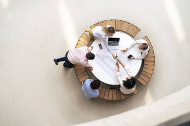 Geschäftskollegen planen über Windkraftanlage, die auf einem Tisch in der Bürolobby steht - JOSEF12270