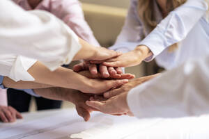 Hands of business colleagues stacking hands in office - JOSEF12318