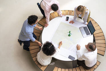 Geschäftsleute, die über ein Diagramm auf einem Tisch im Büro miteinander diskutieren - JOSEF12327