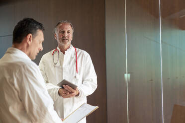 Leitender Arzt mit Tablet-PC und Kollege bei der Prüfung eines Berichts im Krankenhaus - JOSEF12371