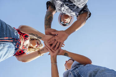 Young friends stacking hands together on sunny day - PGF01206