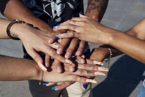 Hands of friends stacked together on sunny day - PGF01210