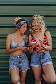Glückliche junge Frauen teilen sich ein Smartphone - PGF01221
