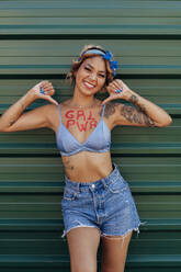 Lächelnde Frau mit Girl Power Text auf der Brust vor einer Wand - PGF01238
