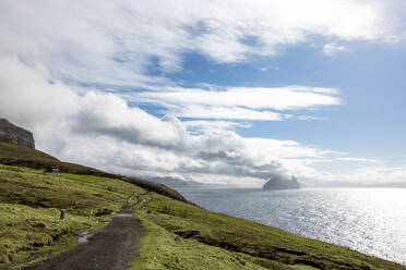 Färöer Inseln, Vagar, Wolken über der Küstenstraße mit Inseln im Hintergrund - WPEF06265