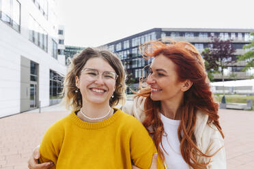 Happy redhead woman with daughter standing at Hafencity - IHF01141