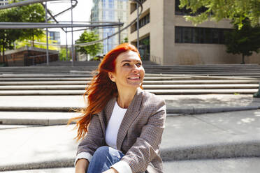 Smiling redhead woman sitting on steps - IHF01152