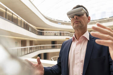 Mature businessman with smart glasses in corridor - JOSEF12435