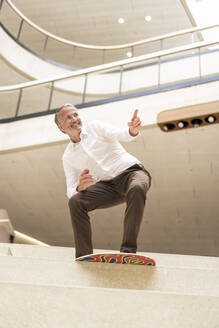 Smiling senior businessman standing on bodyboard - JOSEF12466