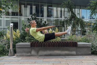 Älterer Mann übt Yoga in Bootsposition auf einer Bank - VPIF07036