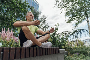 Mature man in lotus position meditating on bench - VPIF07038