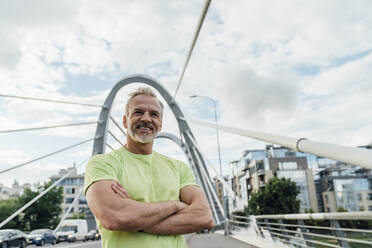 Lächelnder reifer Mann steht auf einer Hängebrücke in der Stadt - VPIF07077