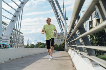 Mature man jogging on bridge in city - VPIF07081