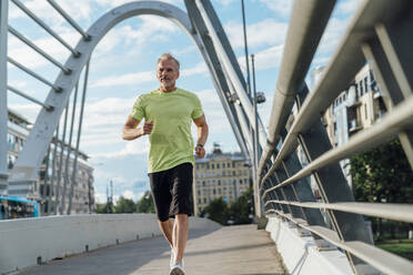 Mature man running on bridge in city - VPIF07082