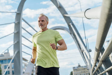 Man running on suspension bridge in city - VPIF07084