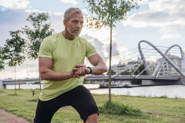 Älterer Mann mit Smartwatch beim Stretching im Park - VPIF07093