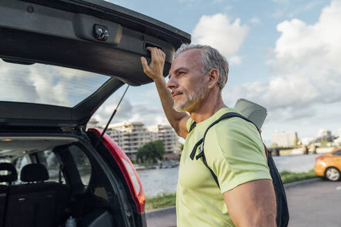 Mature man with gray hair closing car trunk - VPIF07106