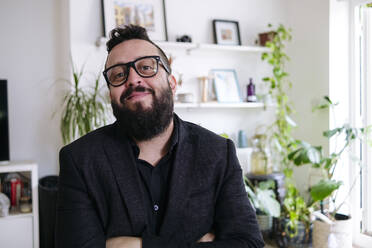 Smiling businessman wearing eyeglasses at home - ASGF02724