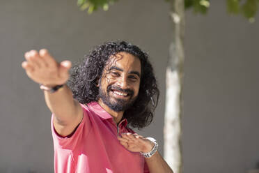 Smiling young man gesturing on sunny day - SGF02917