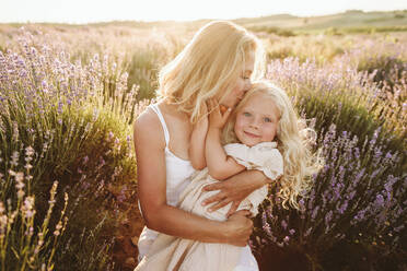 Mother kissing daughter in lavender field - SIF00377