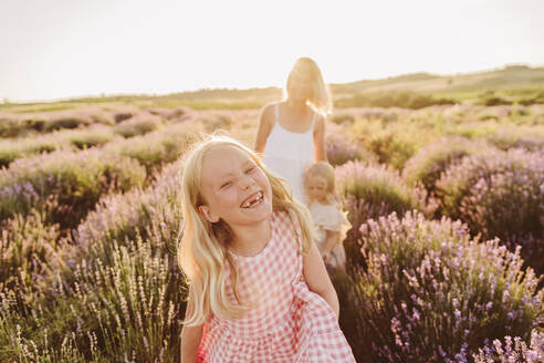 Happy girl enjoying with mother and sister in lavender field - SIF00379