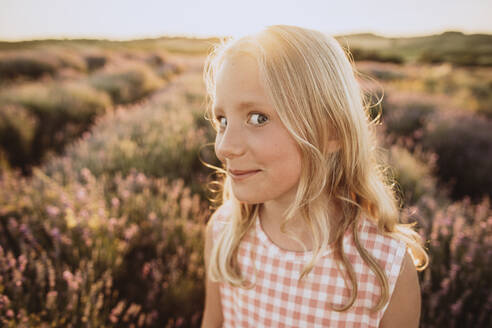 Girl with blond hair making facial expression in lavender field on sunset - SIF00386