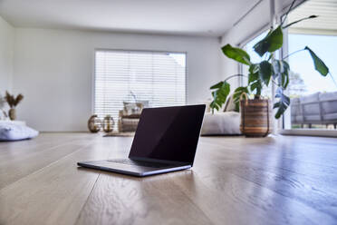 Laptop on floor in living room at home - FMKF07678