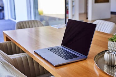 Laptop on wooden dining table at home - FMKF07709