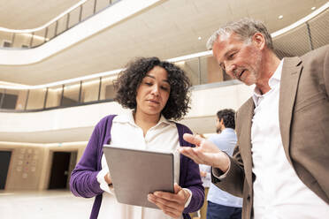 Multirassische Geschäftskollegen diskutieren über Tablet-Computer im Korridor - JOSEF12673