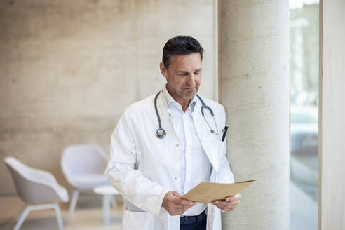 Smiling doctor with report document in hospital - JOSEF12709