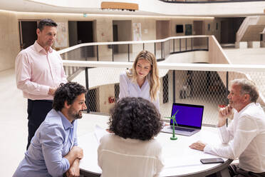 Lächelnde Geschäftskollegen diskutieren Ideen über ein Windturbinenmodell im Korridor - JOSEF12757