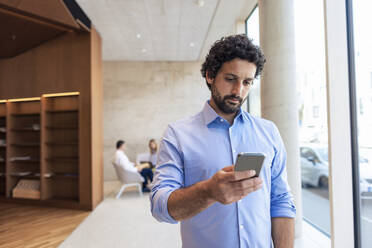 Professor using smart phone in library - JOSEF12770