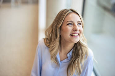 Happy businesswoman looking up in office - JOSEF12783