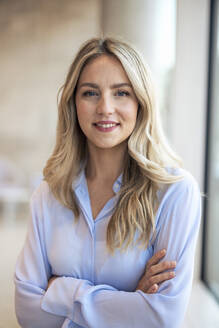 Smiling businesswoman with arms crossed in office - JOSEF12785